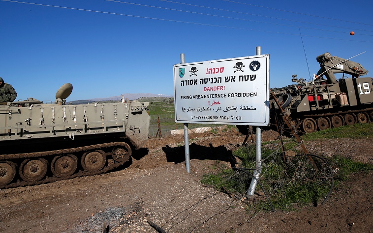 Israeli military vehicles are pictured near a warning sign during a military drill in the Israeli-annexed Golan Heights, on December 30, 2020. – Israeli air strikes in Syria targeting the pro-Damascus Lebanese Hezbollah group and Syrian air defence forces, killed one Syrian soldier and wounded five others, a war monitor said today. (Photo by JALAA MAREY / AFP)