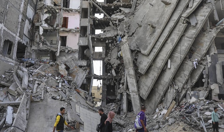 Palestinians walk through destruction in Gaza City on Friday, Nov. 24, 2023, as the temporary ceasefire between Israel and Hamas took effect. (AP Photo/Mohammed Hajjar)